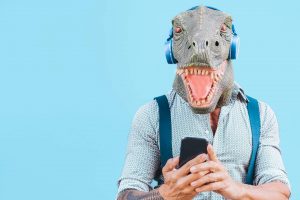 A man wearing a dinosaur mask looking at his phone for stag party ideas