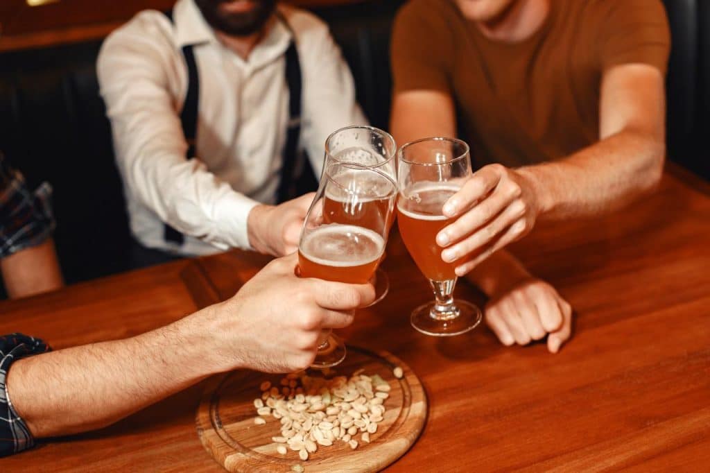 Three men sharing a beer as part of their cheap stag do ideas