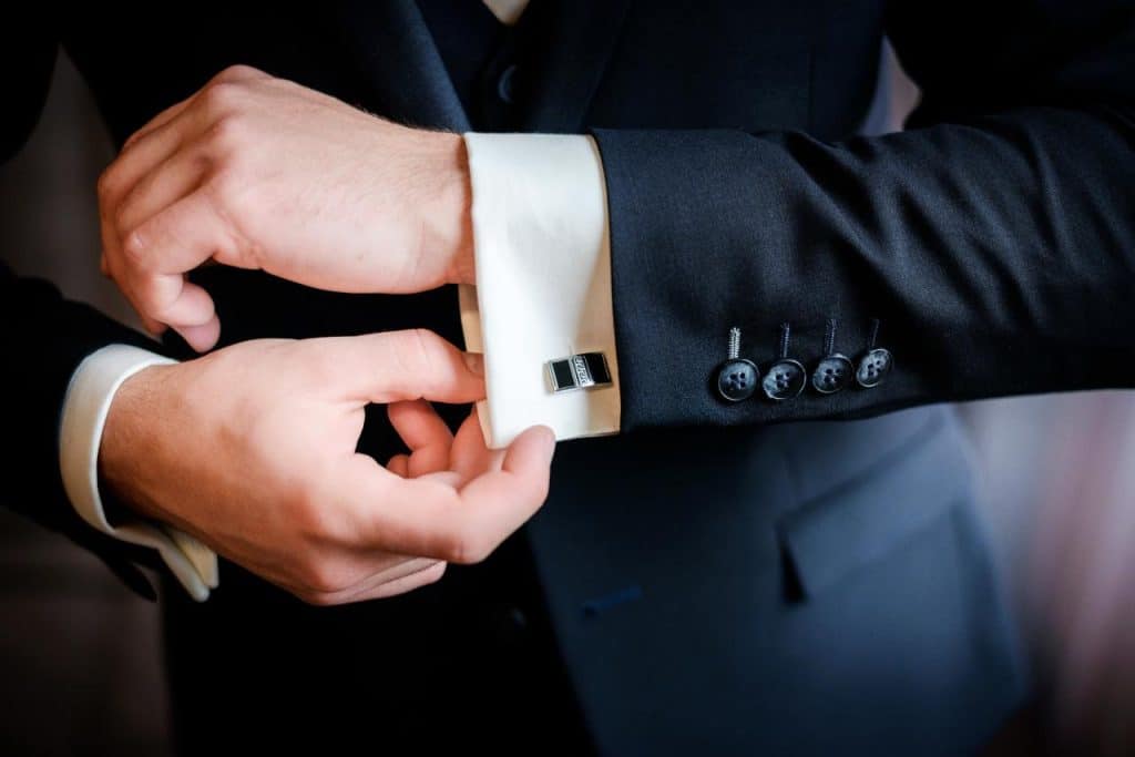 A groom putting on cuff links which were a best man gifts to the groom